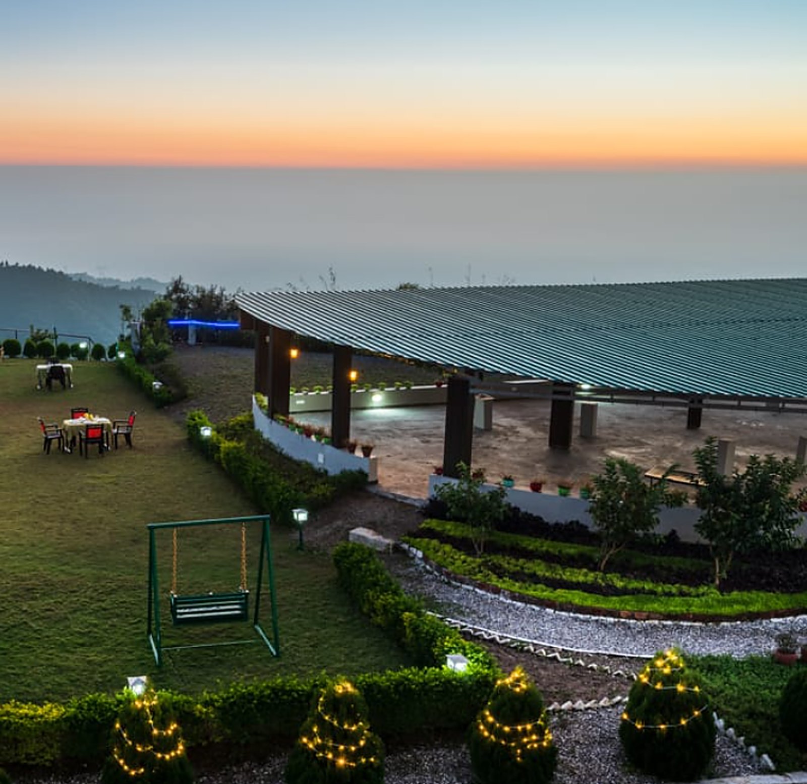 The hilltop lawn at dusk, lanterns lit above a sea of cloud